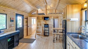 A wooden cabin interior with a kitchen, dining area, and a large window. - Teton Mtn Views: Peaceful Riverfront Cabin! (Ashton)