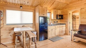 A wooden cabin interior with a kitchen, dining area, and seating. - Teton Mtn Views: Peaceful Riverfront Cabin! (Ashton)