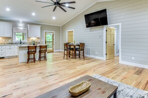 A spacious kitchen with wooden flooring, a dining area with a table and chairs, and a ceiling fan.