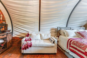 A cozy tented room with a sofa, a bed, and a wooden cabinet.