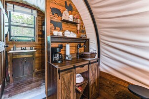 Cocina compacta con armarios de madera, cafetera y estantes con utensilios de cocina.