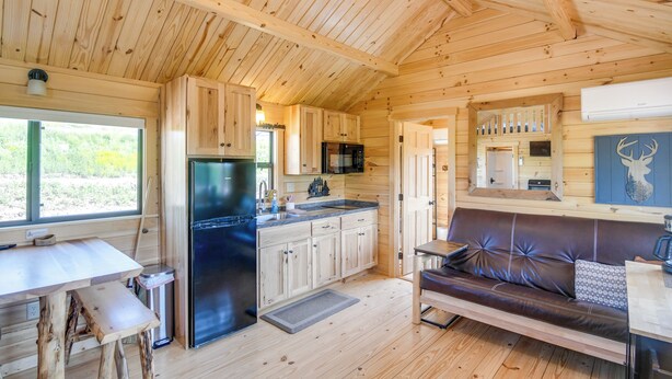 Una cabaña de madera con cocina, comedor y un sofá de cuero.