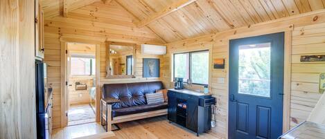 A wooden cabin interior with a sofa, coffee table, and a grill.