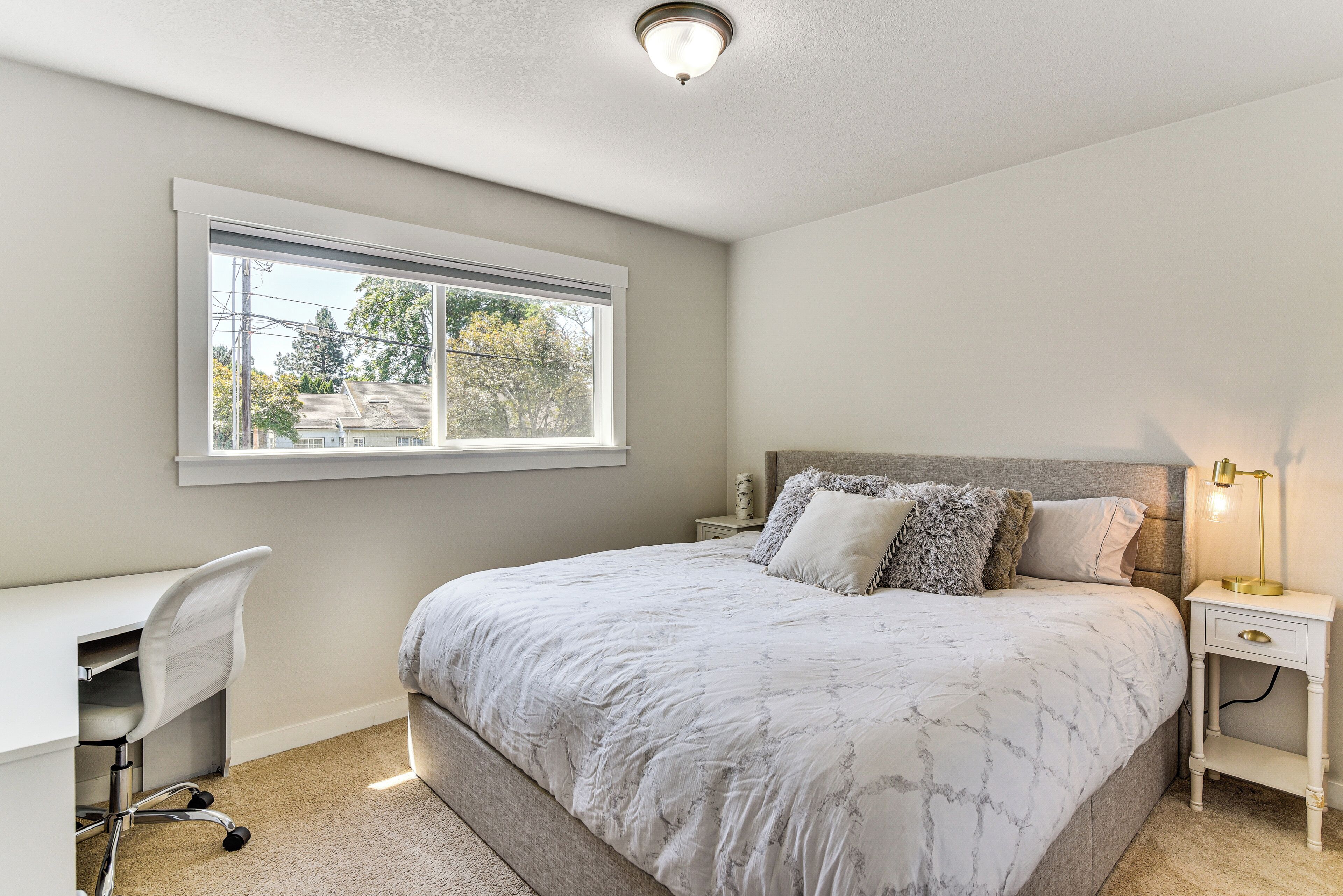 A bedroom with a large bed, a desk, and a nightstand.