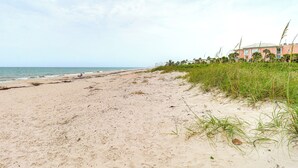 Ein Strand mit einem Gebäude im Hintergrund.