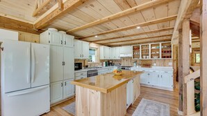 A spacious kitchen with wooden beams, white cabinets, and a central island. - Dock + Kayaks: Annabessacook Lake Retreat! (Winthrop)