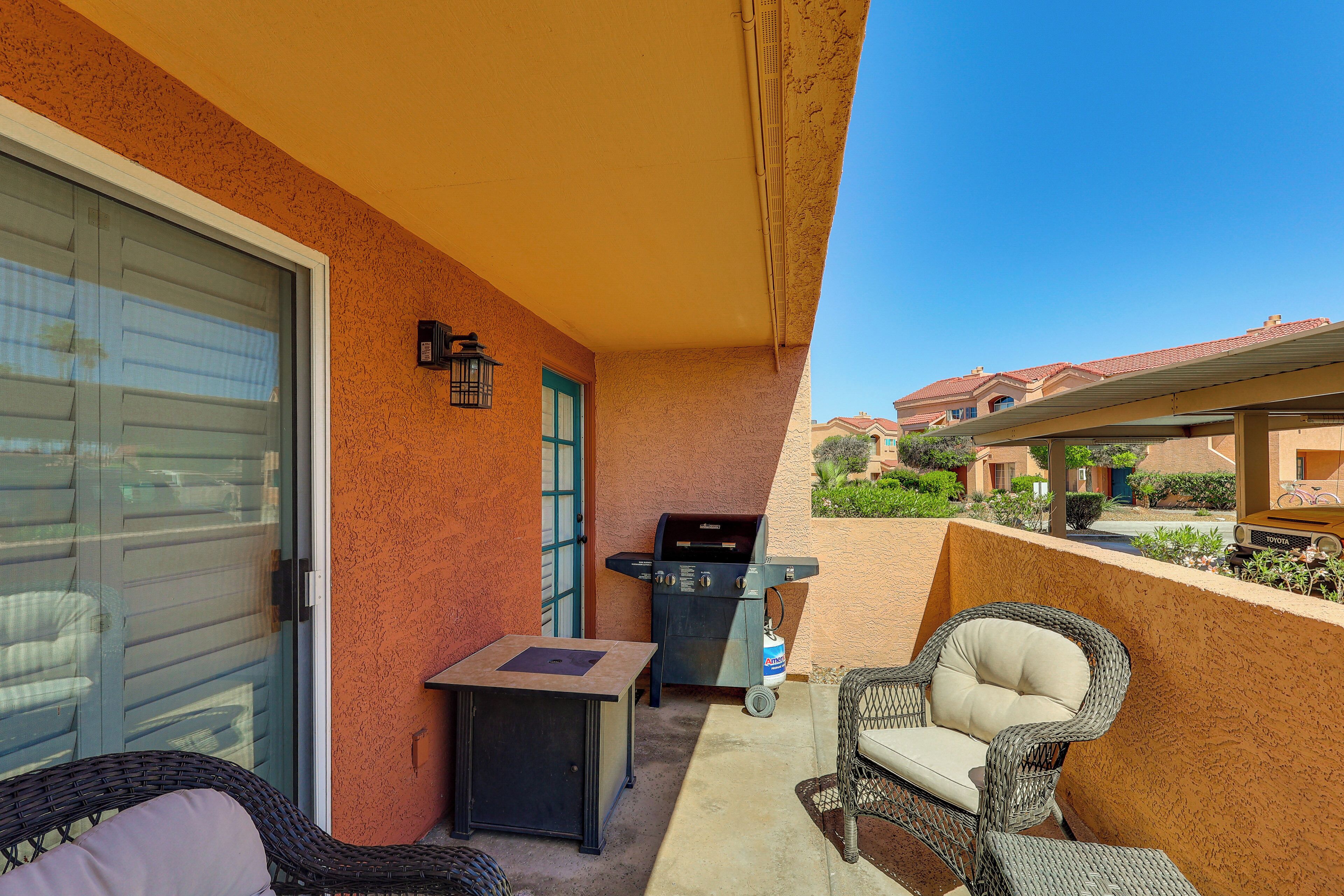 An outdoor patio with a grill, wicker furniture, and a view of neighboring houses.