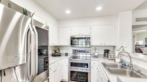 A modern kitchen with stainless steel appliances, white cabinetry, and a built-in oven. - Walk to Rotary Park: LHC Condo w/ Private Patio (Lake Havasu City)