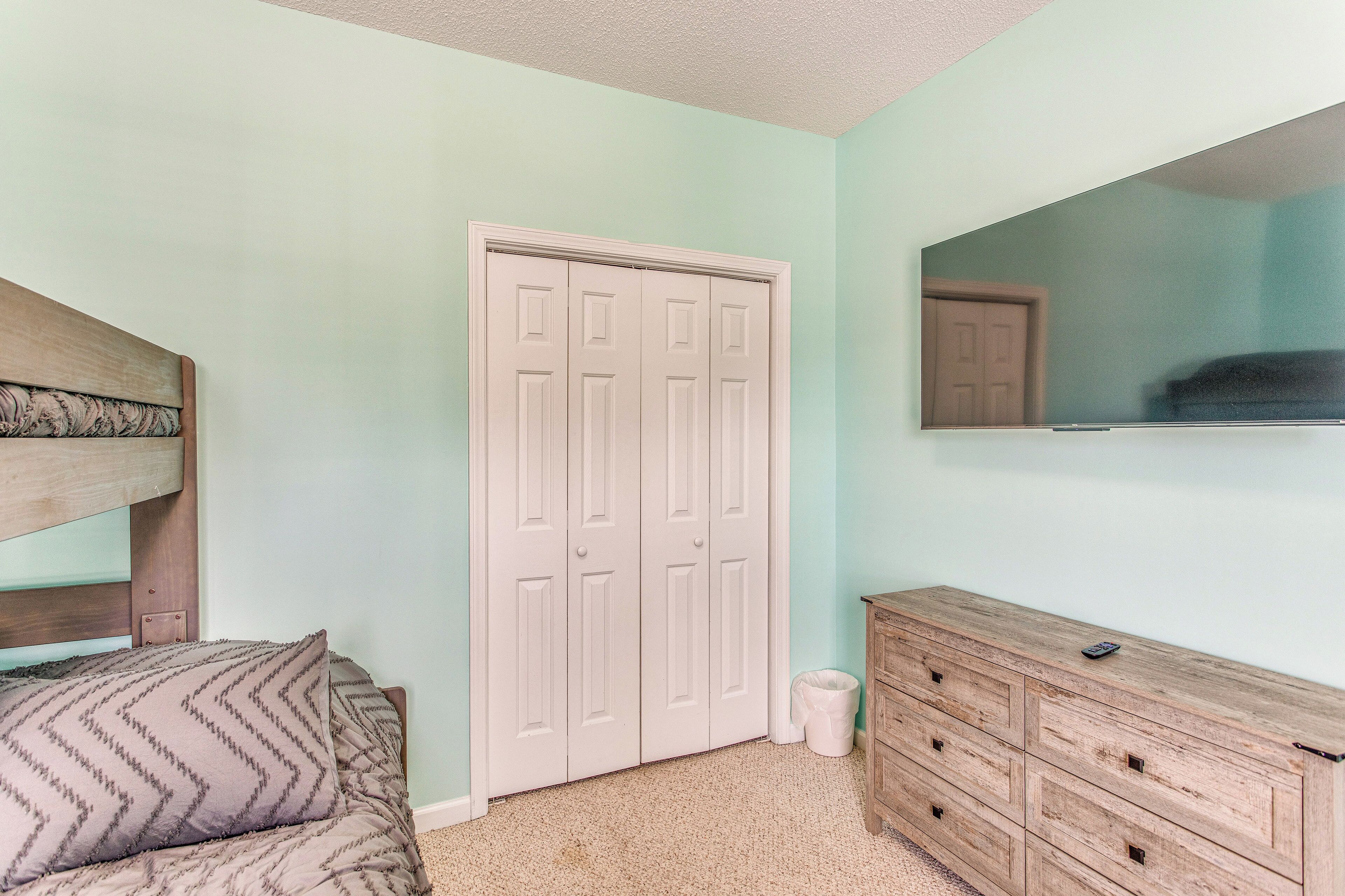 A bedroom with a bed, a dresser, a closet, and a mirror.