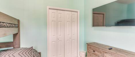 A bedroom with a bed, a dresser, a closet, and a mirror.