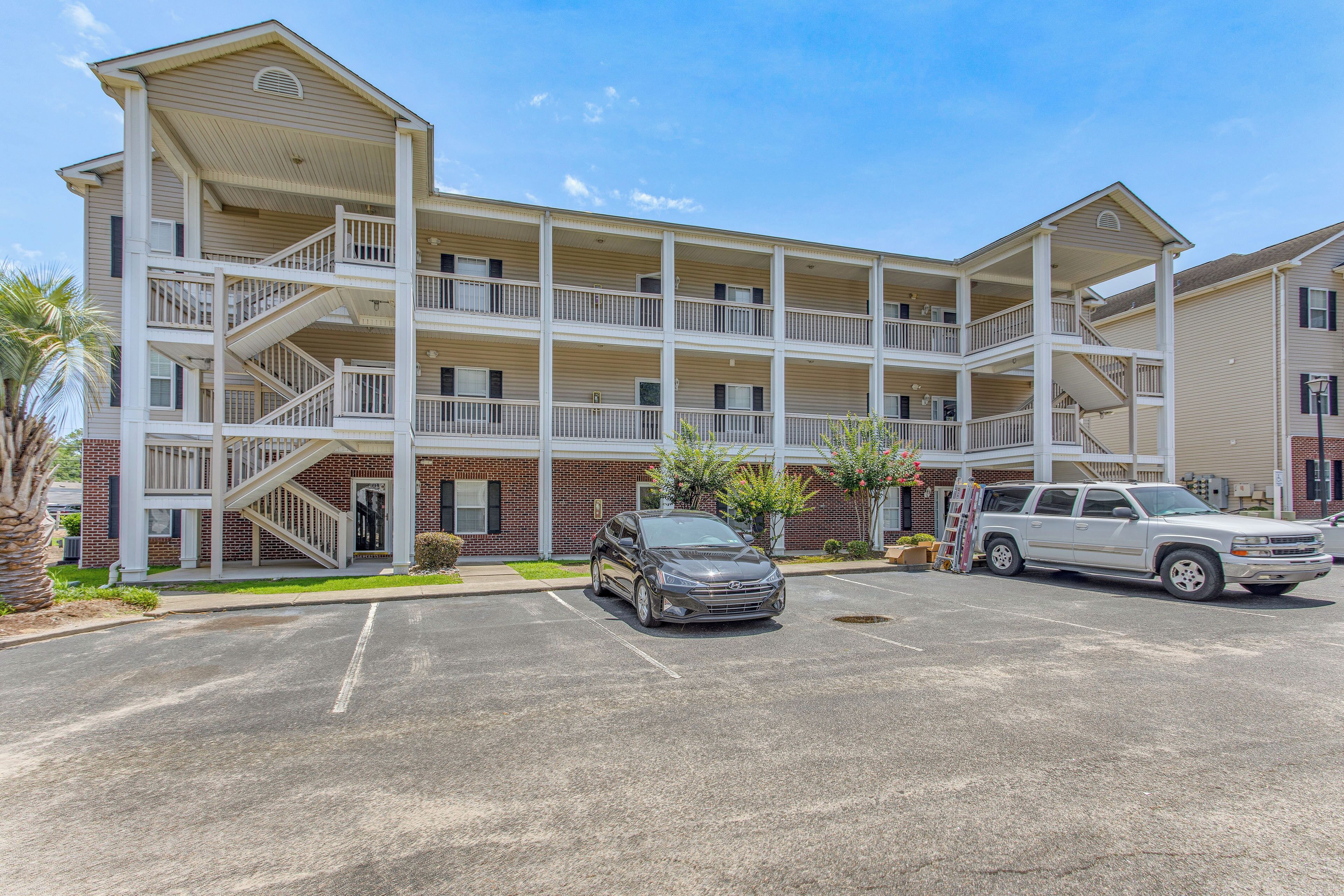 A multi-story motel with a central atrium, multiple balconies, and a parking lot with two vehicles.