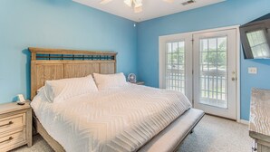 Une chambre à coucher avec un lit, une tête de lit en bois, une table de chevet et un ventilateur de plafond.