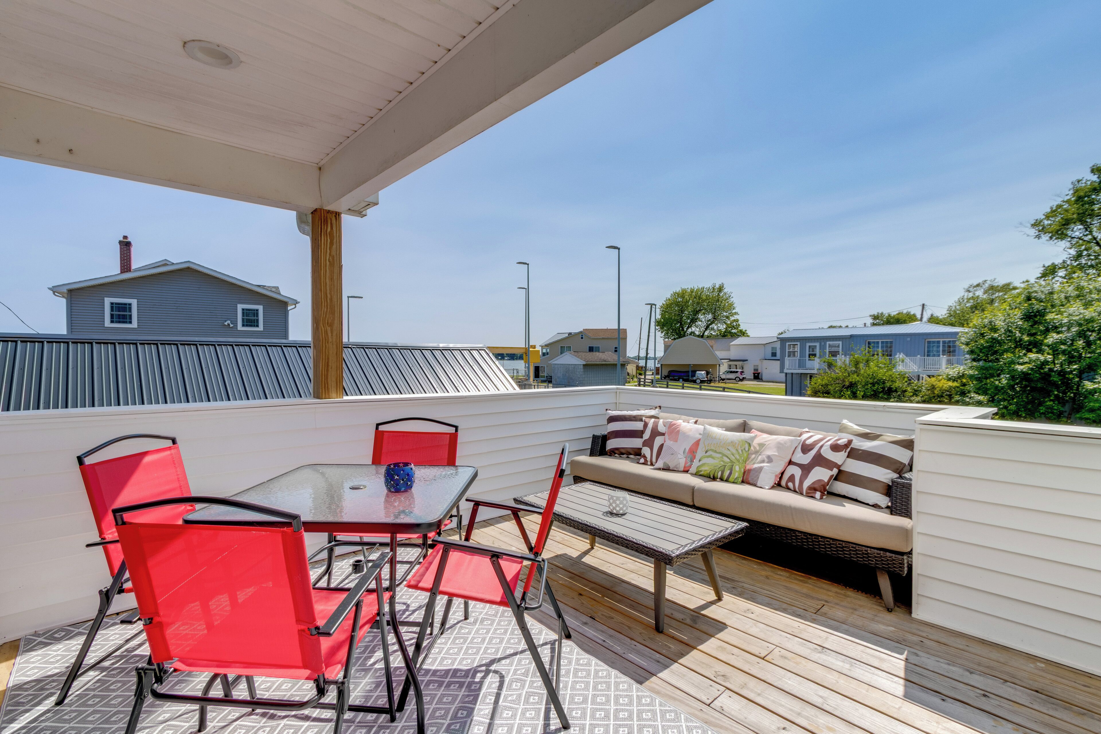 Une terrasse extérieure couverte, avec une table et des chaises, un canapé et une vue sur les maisons voisines.