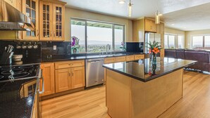 A modern kitchen with wooden cabinets, a black countertop, and a large island.