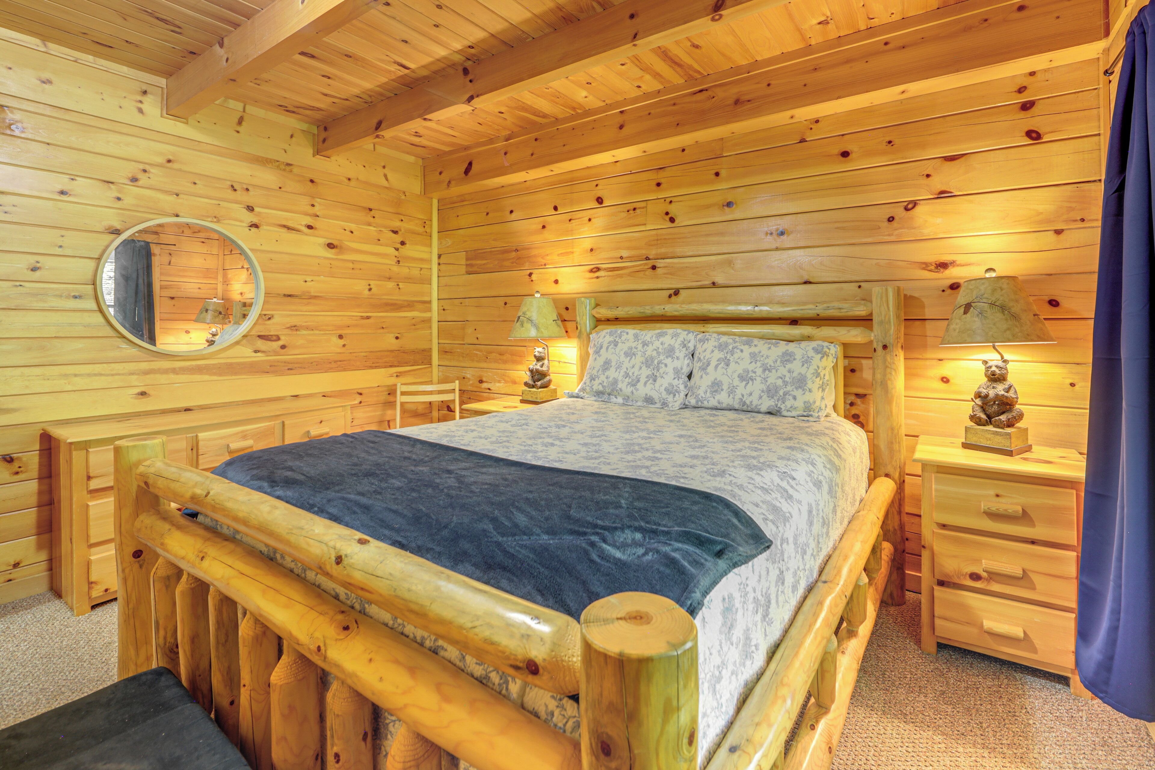 Een slaapkamer in een houten chalet, met een bed, nachtkastjes, een spiegel en een lamp.