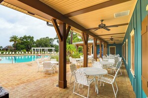 A covered outdoor area with a pool, white metal chairs, and tables. - 6 Mi to Lake Sumter Landing: Home w/ Perks! (The Villages)