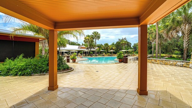 A covered outdoor area with a pool, palm trees, and a tiled floor. - 6 Mi to Lake Sumter Landing: Home w/ Perks! (The Villages)