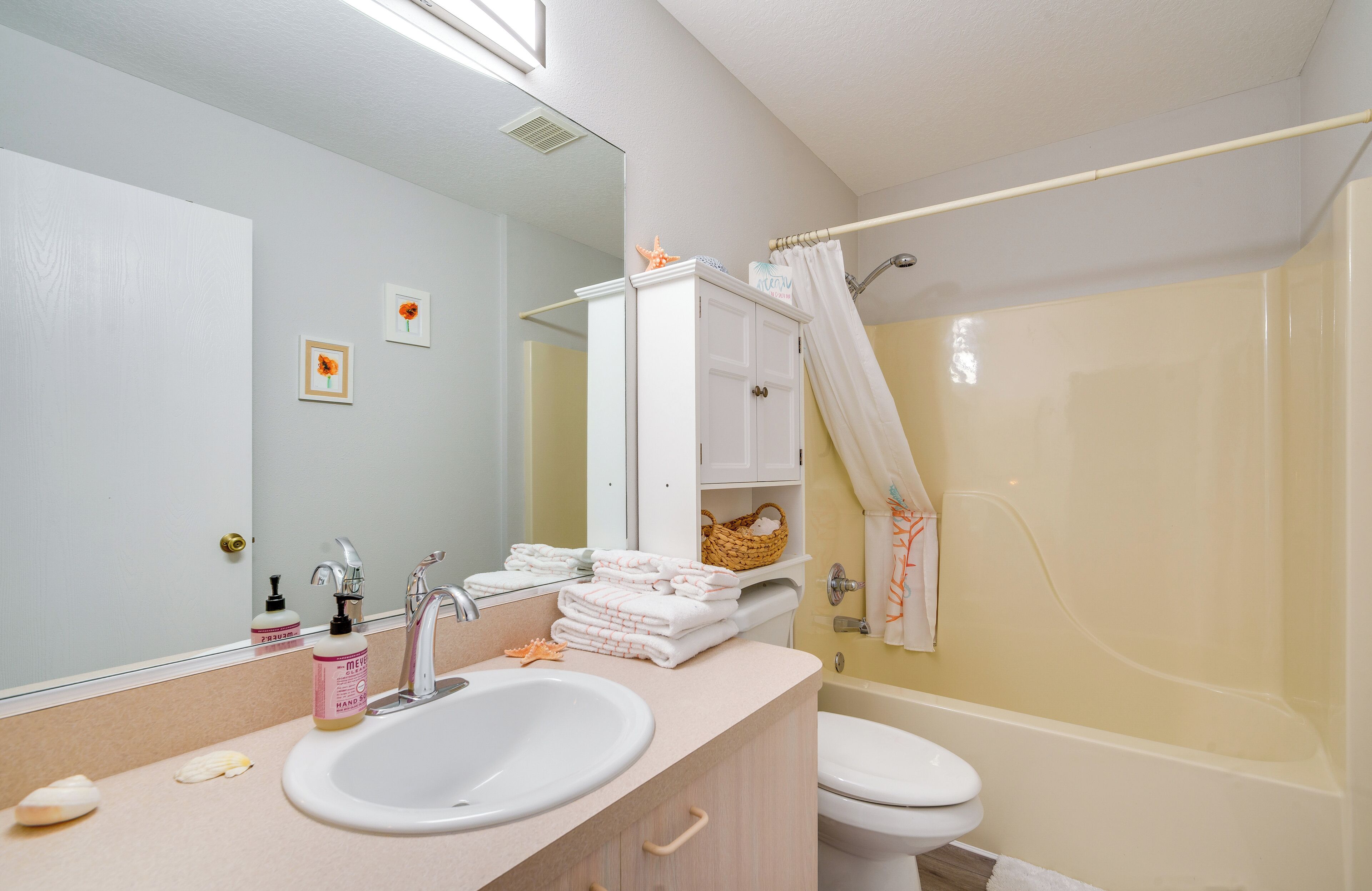 Een badkamer met een wastafel, spiegel, toilet en bad.