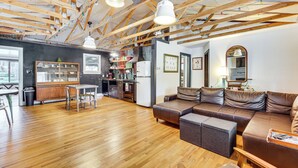 A spacious living area with a wooden ceiling, a brown leather sofa, a dining table, and a kitchen in the background. - 1 Mi to Town: Woodland Park Home w/ Yard! (Woodland Park)