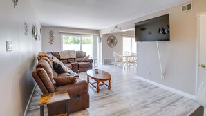 A spacious living room with a brown leather sofa, a wooden coffee table, and a flat-screen TV mounted on the wall. - Walk to Brigantine Beach: Condo w/ Furnished Patio (Brigantine)
