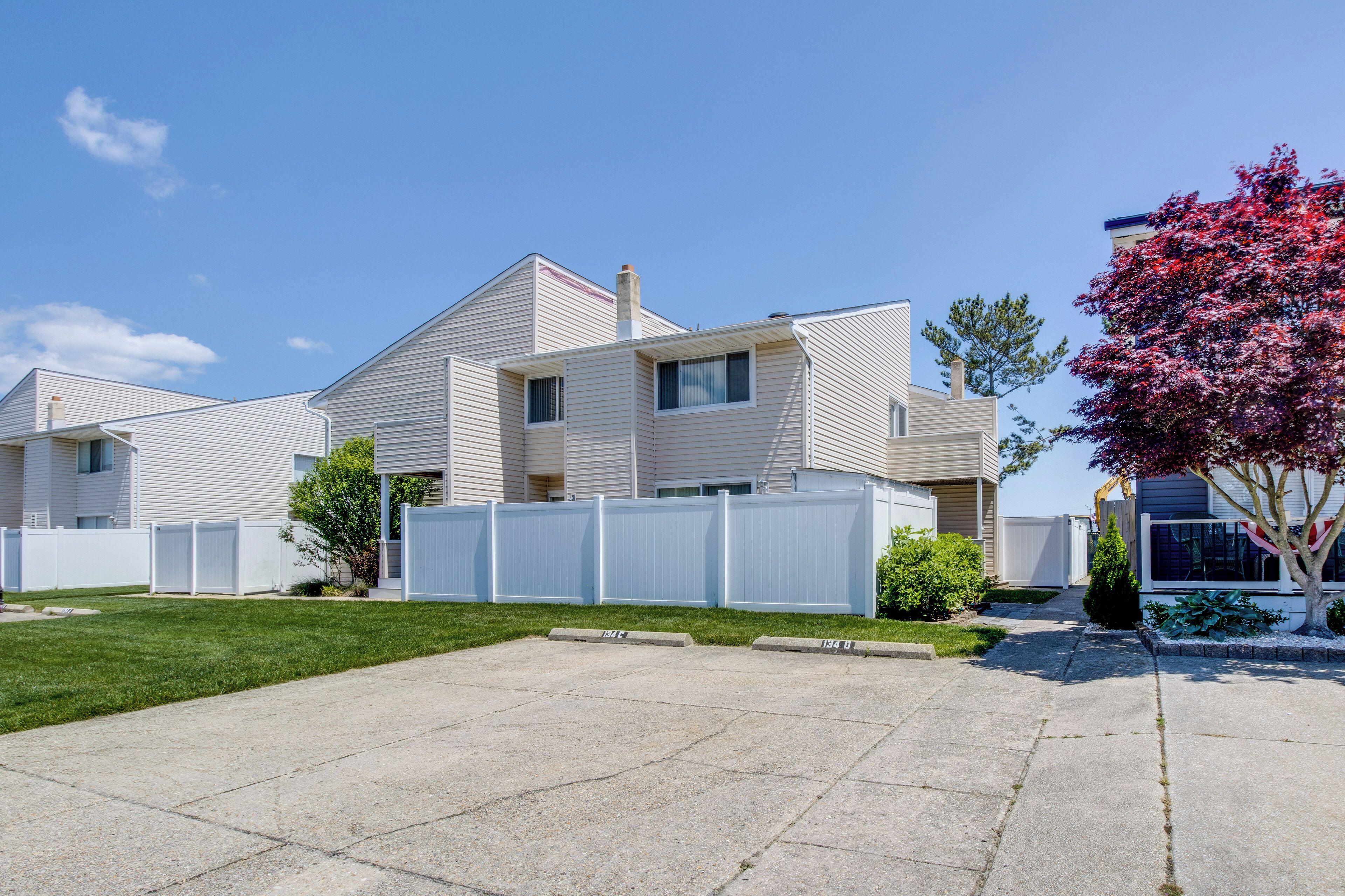 A modern two-story house with a front yard and a white picket fence.