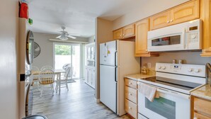 A kitchen with wooden cabinets, a refrigerator, a microwave, and an oven. - Walk to Brigantine Beach: Condo w/ Furnished Patio (Brigantine)