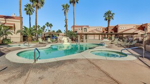 A pool area with two pools, palm trees, lounge chairs, and a building with a red roof. - 1 Mi to Beach: Lake Havasu City Condo w/ Balcony (Lake Havasu City)