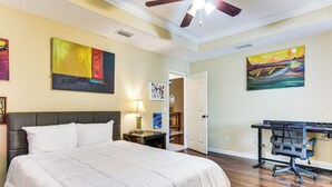 Une chambre avec un grand lit, un bureau et deux tableaux accrochés aux murs.