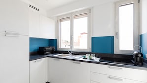 A modern kitchen with white cabinets, a black countertop, and a window with a view of buildings outside. - Casa Brezza Marina by Wonderful Italy (Olbia)