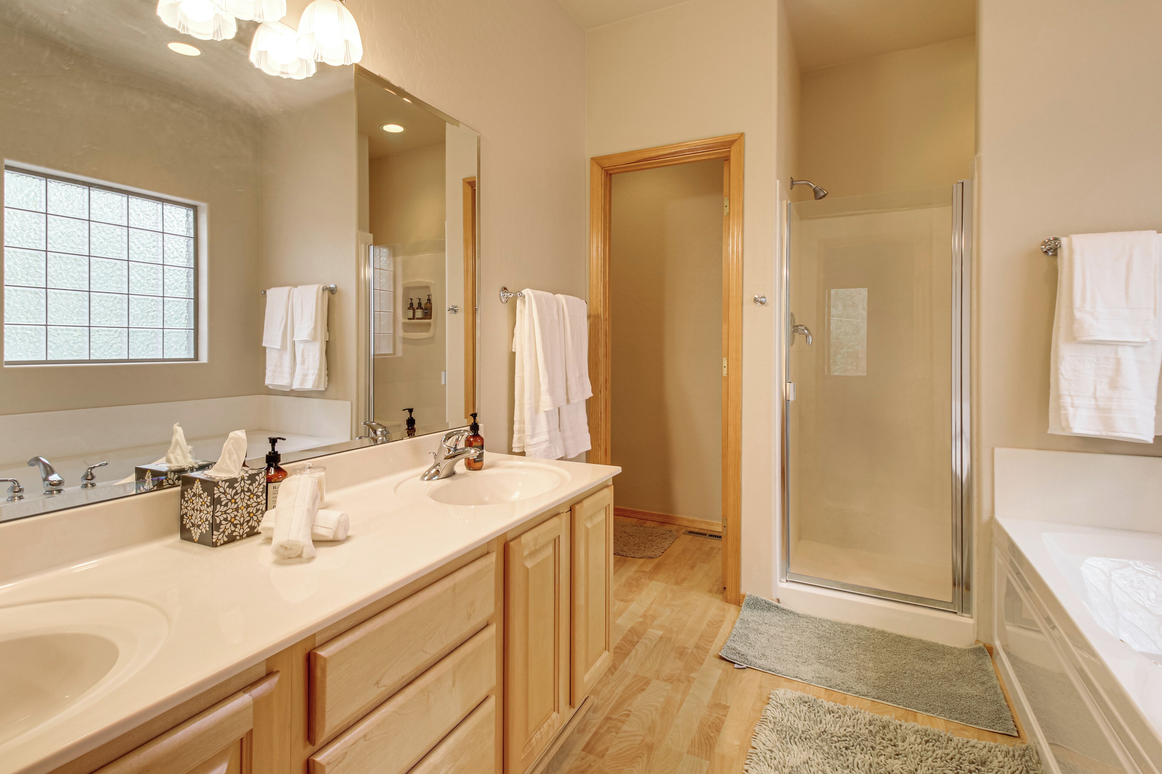 A bathroom with two sinks, a large mirror, and a walk-in shower.