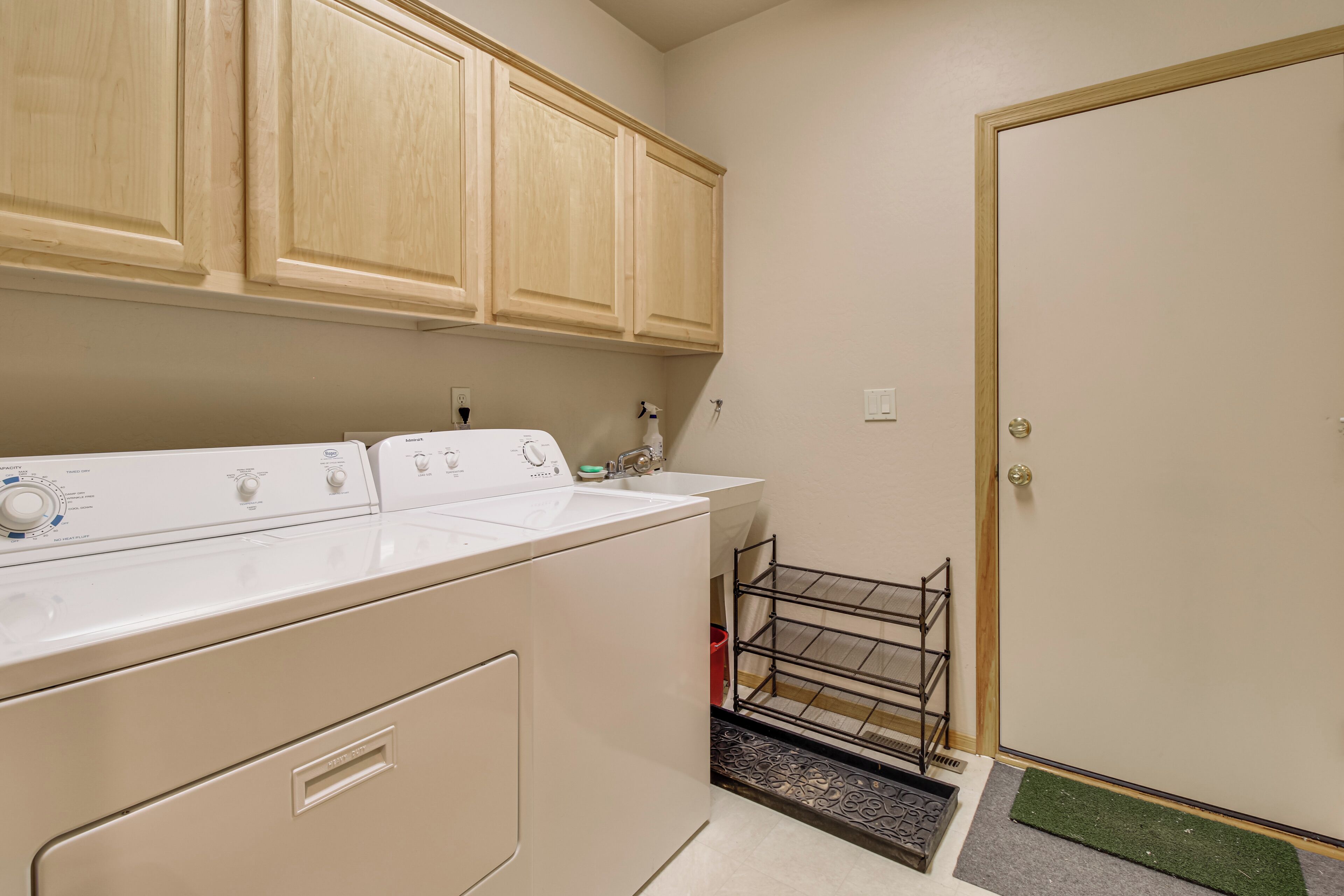 A laundry area with a washing machine, dryer, and a metal rack for hanging clothes.