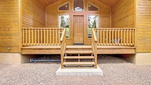 Eine Holzhütte mit Veranda, einer Treppe zum Eingang und einem Kiesgrundstück.