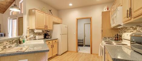 A kitchen with wooden cabinets, granite countertops, a refrigerator, stove, and a microwave.