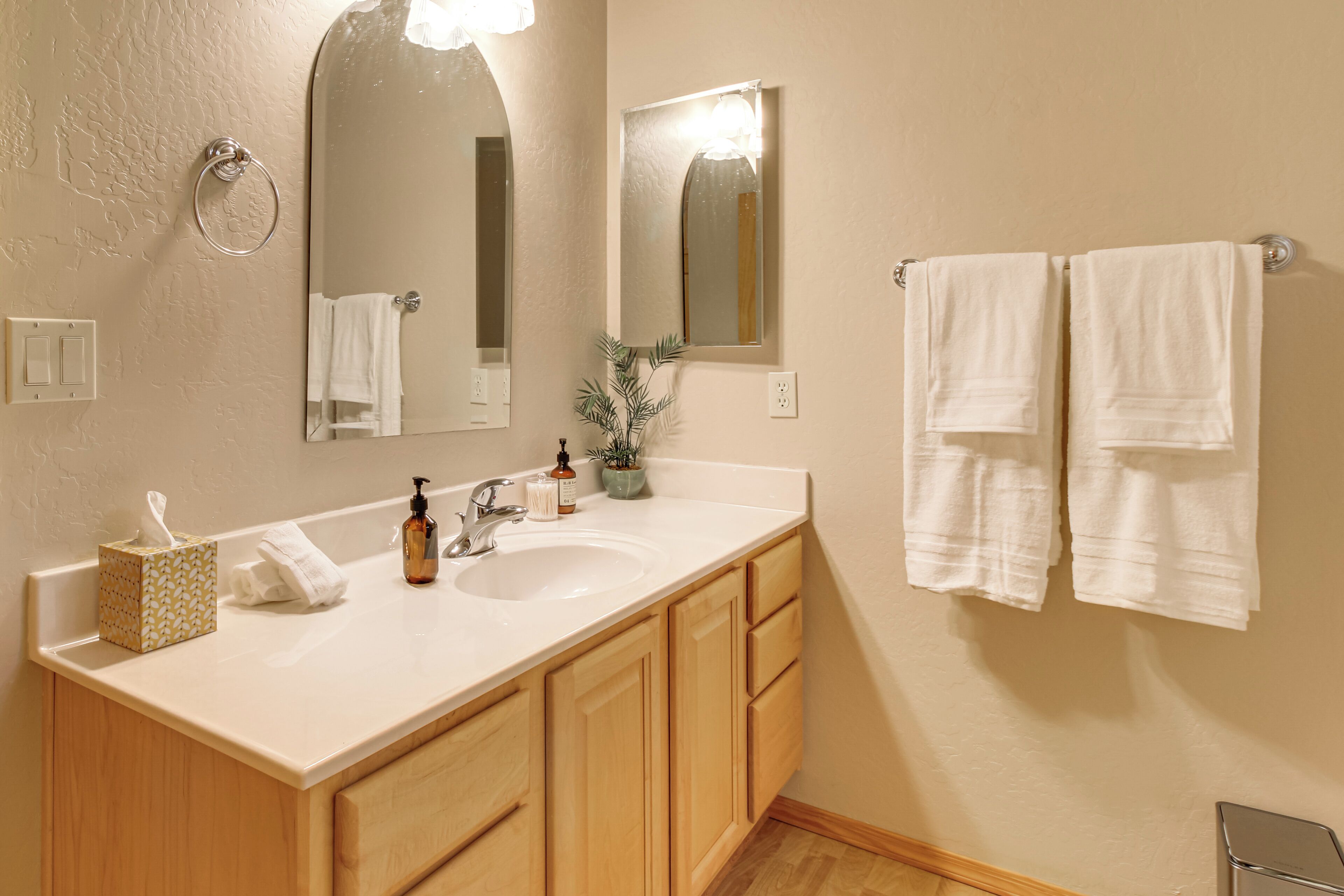 A bathroom with a sink, mirror, towel rack, and wooden cabinets.