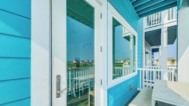 A blue wooden deck with white railings and a table. - Walk to Beaches: Padre Island Escape w/ Dock (Corpus Christi)