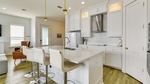 A modern kitchen with white cabinetry, a central island with bar stools, stainless steel appliances, and pendant lighting. - Walk to Beaches: Padre Island Escape w/ Dock (Corpus Christi)