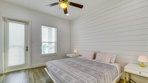 A bedroom with a bed, a nightstand, a ceiling fan, and a window with blinds. - Walk to Beaches: Padre Island Escape w/ Dock (Corpus Christi)