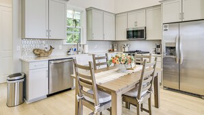 A modern kitchen with white cabinetry, stainless steel appliances, and a wooden dining table with chairs. - Walk to Boat Ramp: Lake Greenwood Getaway! (Greenwood)