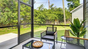 A balcony with a glass table, a wicker basket, and a chair with a cushion. - Walk to Boat Ramp: Lake Greenwood Getaway! (Greenwood)