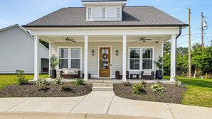 A two-story house with a front porch, a wooden front door, and a small garden area with stepping stones leading to the entrance. - Walk to Boat Ramp: Lake Greenwood Getaway! (Greenwood)