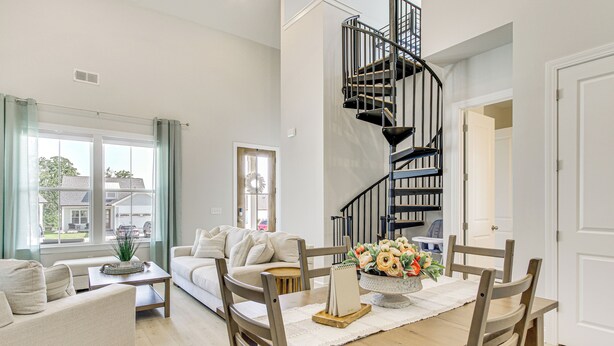 A spacious living room with a wooden dining table, beige sofas, and a black spiral staircase. - Walk to Boat Ramp: Lake Greenwood Getaway! (Greenwood)