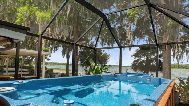 Un bain à remous situé dans un espace abrité, offrant une vue sur les arbres et l’eau.