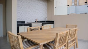 Una cocina moderna con salpicadero de azulejos, una mesa de comedor con seis sillas de mimbre y un amplio ventanal con vistas a un edificio.