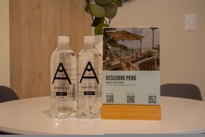 Two bottles labeled 'andea' on a table with a brochure titled 'DESCUBRE PERÚ' and a QR code.