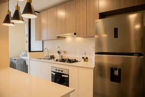 A modern kitchen with stainless steel appliances, wooden cabinets, and pendant lighting.