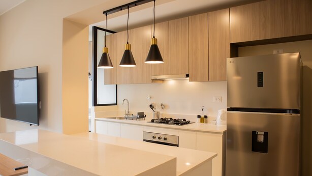 Una cocina moderna con una isla central, electrodomésticos de acero inoxidable e iluminación colgante.
