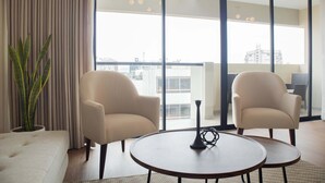 A modern living room with two armchairs, a round coffee table, and a potted plant.