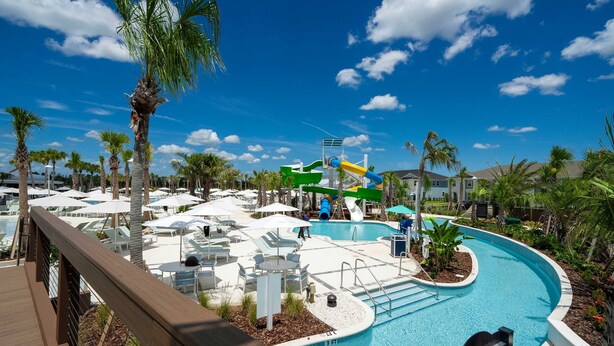 A pool area with lounge chairs, umbrellas, and a water slide. - 16037 Dream Vacation Family Home 5BD (Clermont)
