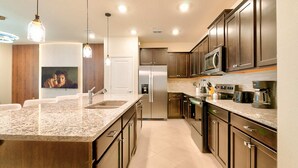 A modern kitchen with granite countertops, stainless steel appliances, and wooden cabinets. - 16037 Dream Vacation Family Home 5BD (Clermont)