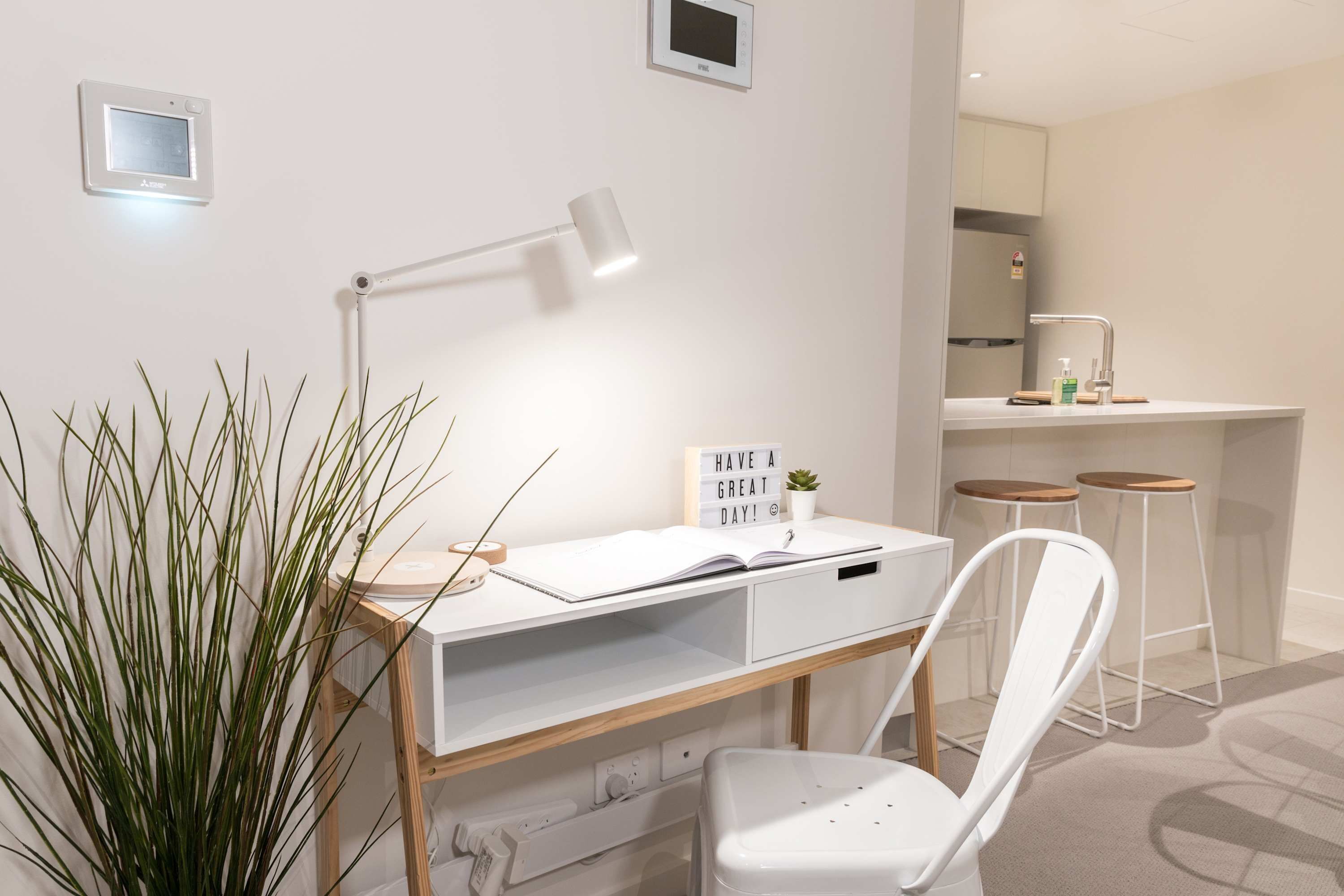 A modern workspace with a desk, chair, lamp, and a motivational sign.